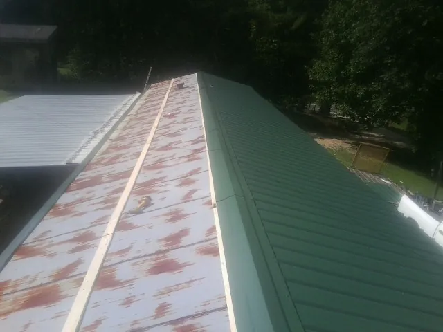 Old rusted panels beside newly installed green metal roofing — Wind Damage Roof Repair by Roofing Brothers in New Meadows