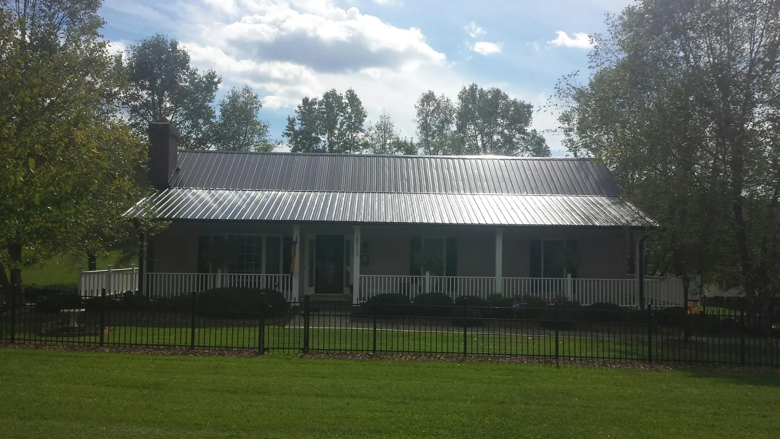 Gray metal roof on a brick ranch with a full width front porch — Gutter Guard Installation work by our crew in New Meadows