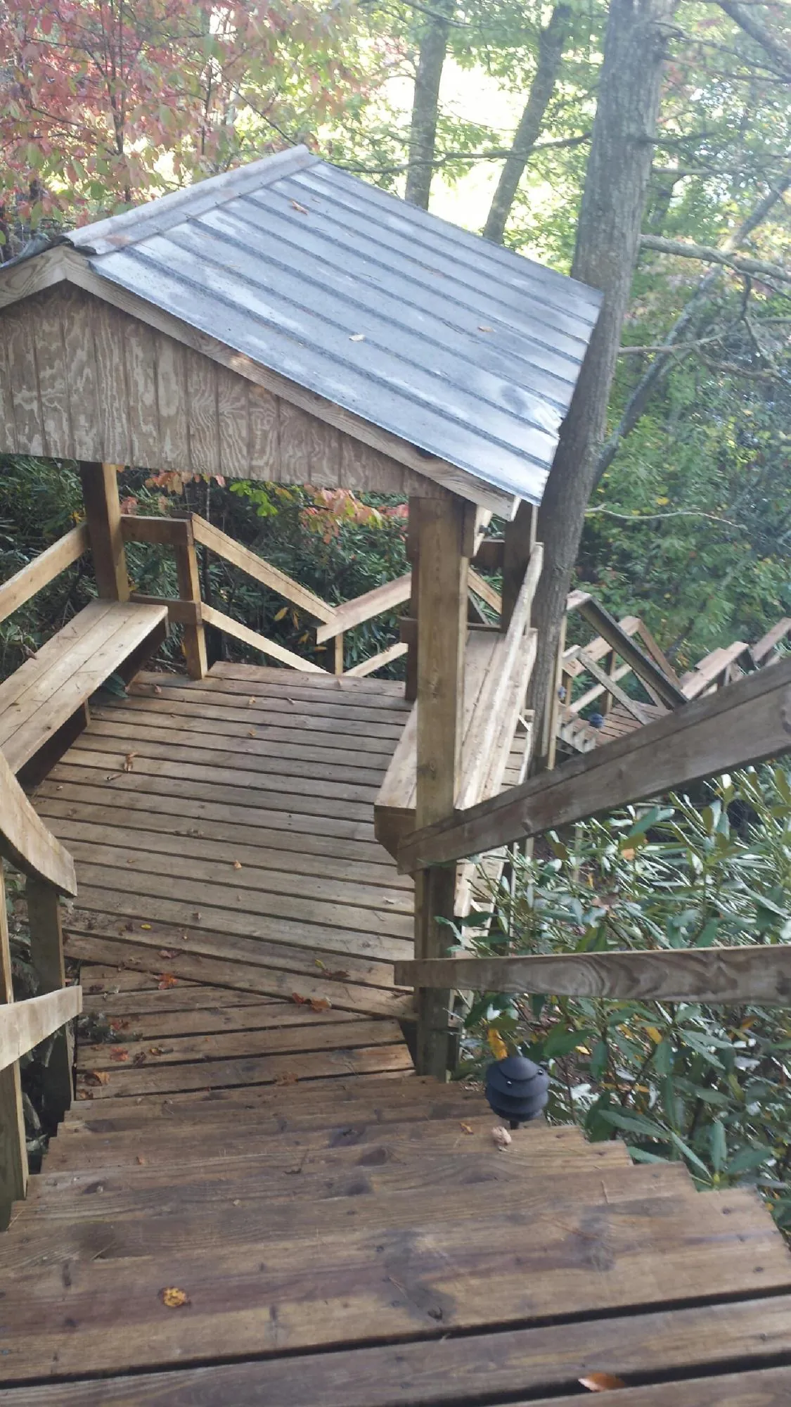 Metal roofed shelter over wooden steps on a wooded walkway — Skylight Repair & Installation work by our crew in New Meadows