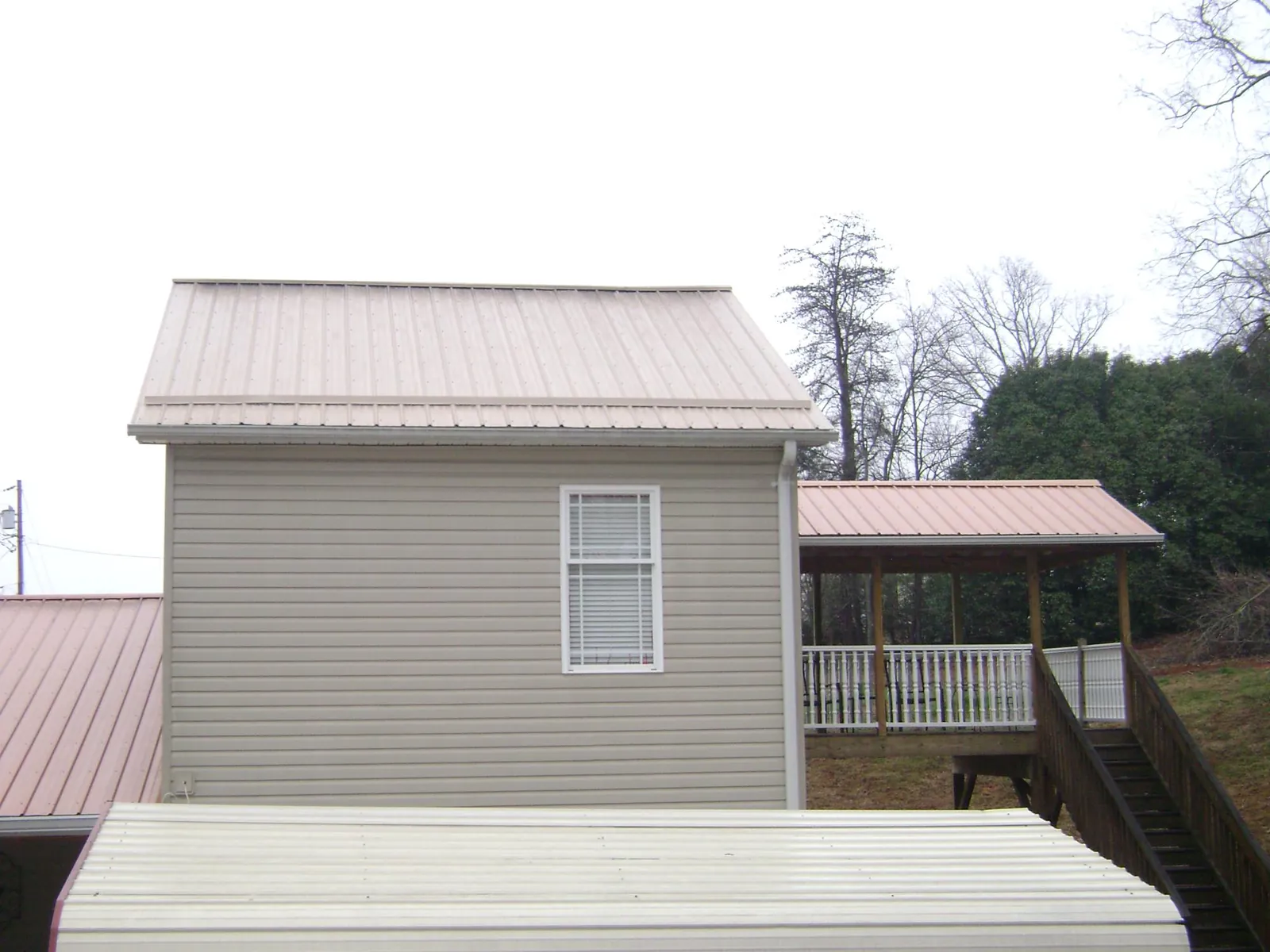 Tan metal roofs on a two story addition and attached porch, from a Roof Replacement job in New Meadows